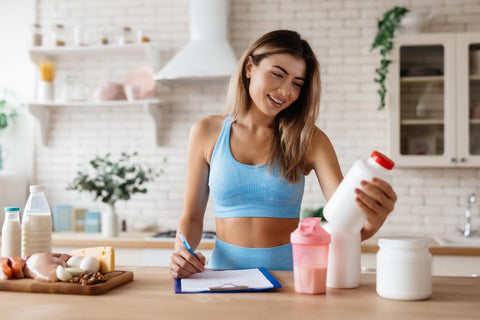 Cele mai recomandate pre-workout fara cofeina (femeie care citeste eticheta unui produs, supliment sportiv, alimentatie sportiva)