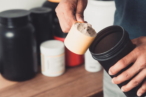 Sunt vegan si fac sala (barbat care isi pune o cupa de proteina in shaker, shake protein, gustare inainte de sala)